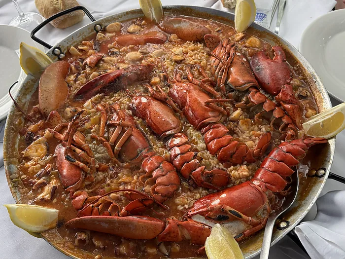 Paellera con arroz de bogavante y marisco, con los bogavantes abiertos encima.