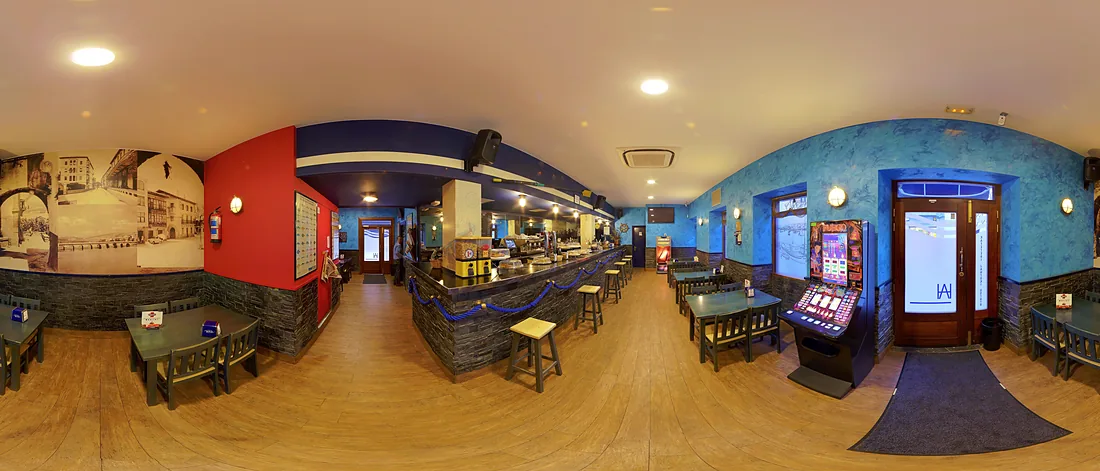 El comedor del Arrarte visto de lado a lado: paredes azules y rojas, suelo de madera y mesas preparadas.