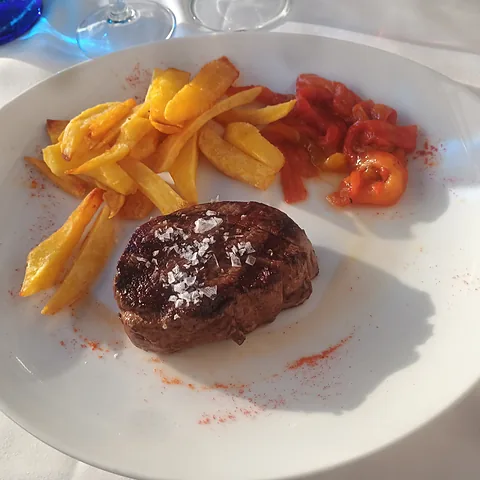 Solomillo a la plancha con patatas fritas y pimientos rojos.