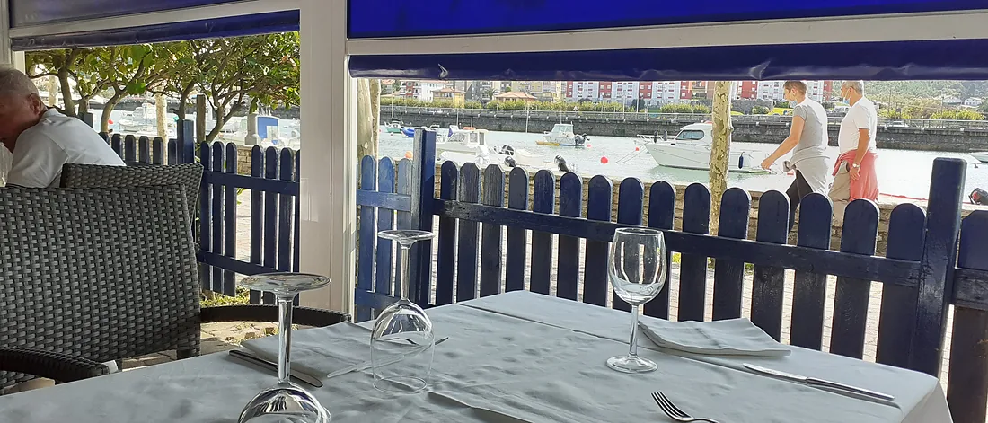 La terraza del Arrarte: mesa puesta con mantel blanco, la valla blanca y, detrás, la ría de Plentzia.